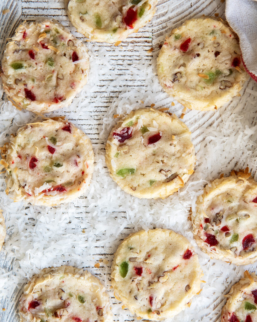 An above view of santa's whiskers cookies filled with red and green cherry pieces.