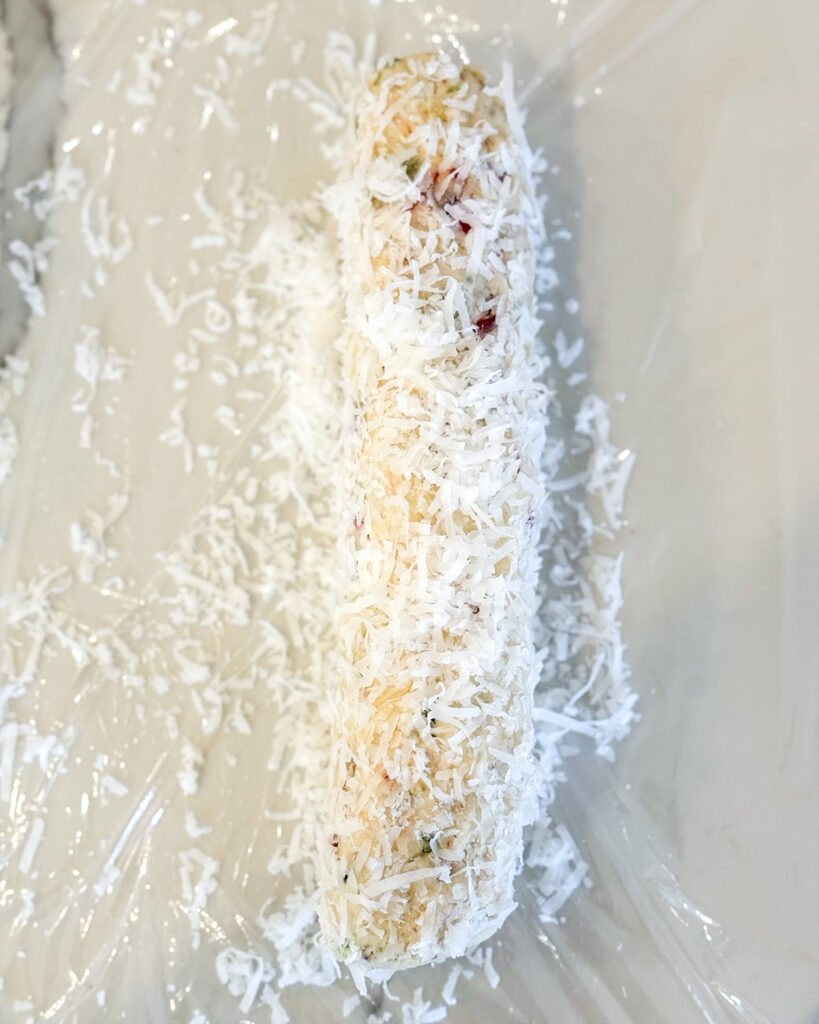 A log of shortbread cookie dough coated in shredded coconut.
