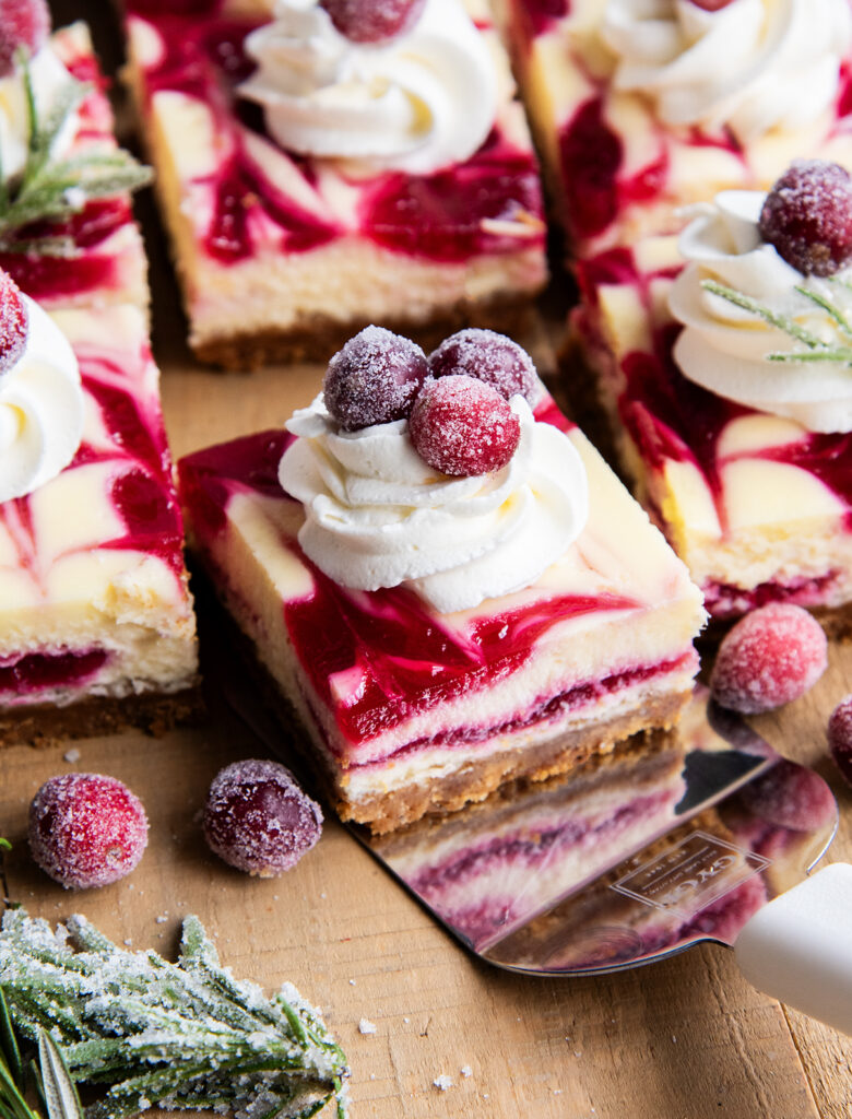 A piece of cranberry swirled cheesecake on a metal spatula.