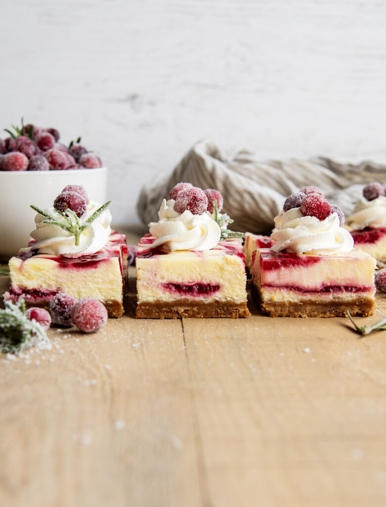 A side view of cranberry cheesecake bars topped with whipped cream.