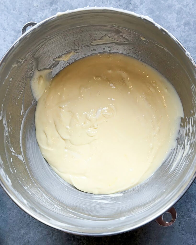 Cheesecake filling in a large metal bowl.