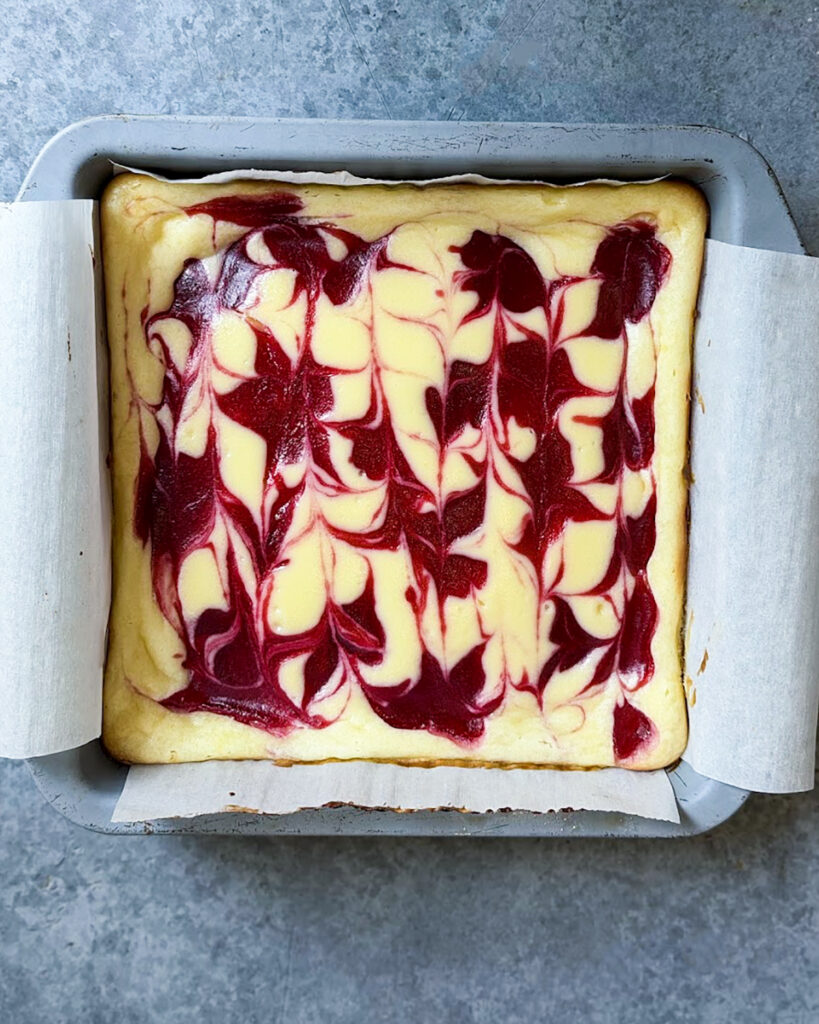 An above view of baked cranberry swirled cheesecake bars.