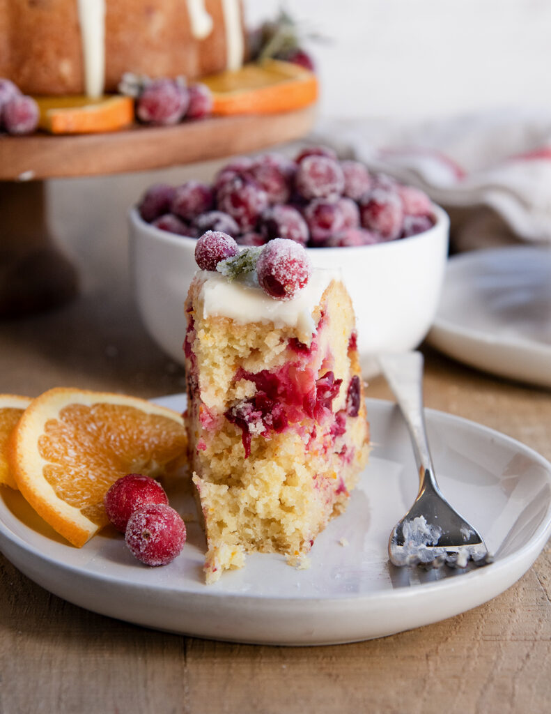 A slice of cranberry bundt cake on a plate with a forkful removed.