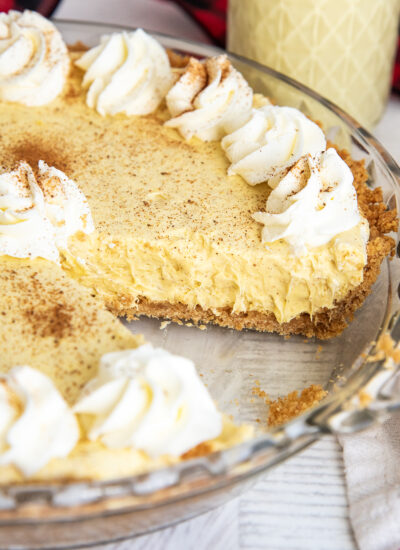 An eggnog pie in a pie plate, topped with whipped cream all around the edges.