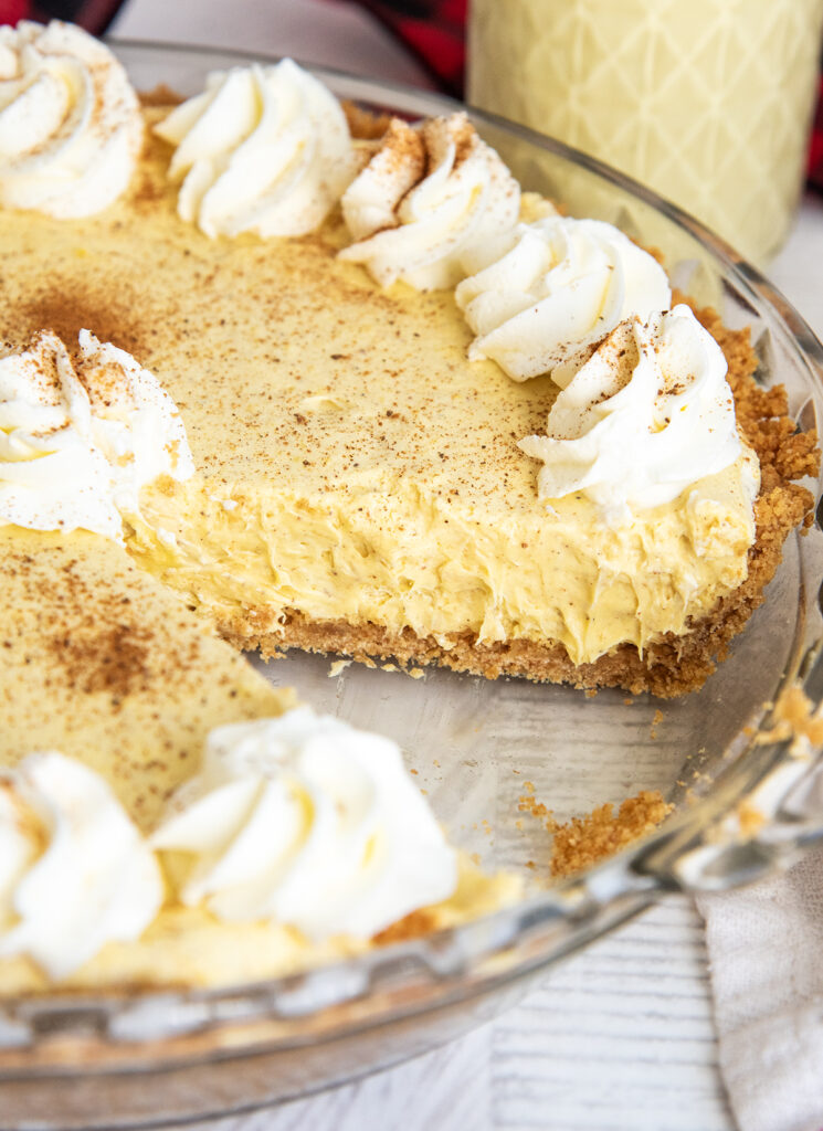 An eggnog pie in a pie plate, topped with whipped cream all around the edges.
