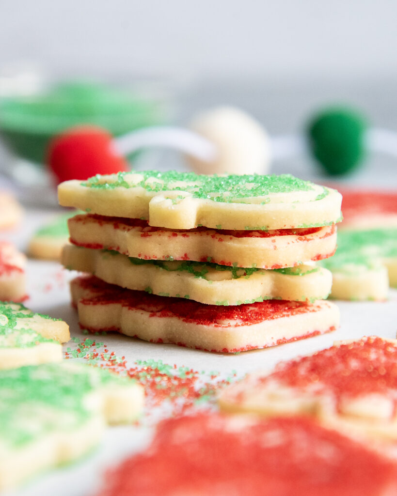 A stack of four shortbread cookies topped with green and red sugars.