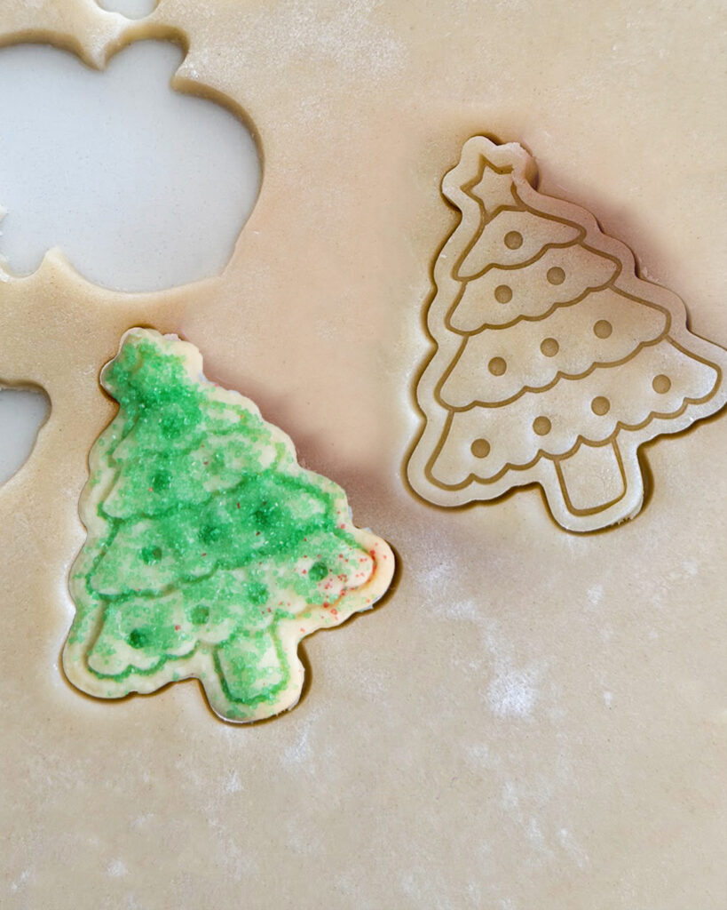 Two cookie dough cookies, one is covered in green sprinkles