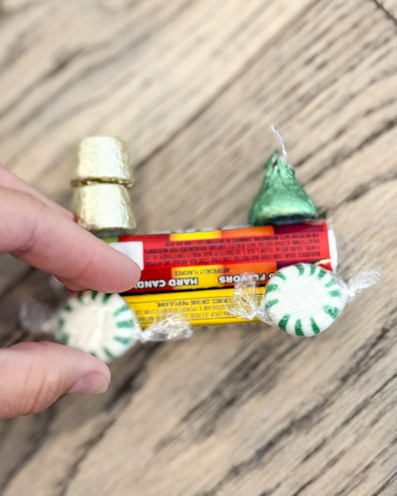 A hand gluing a green starlight mint onto a candy train.