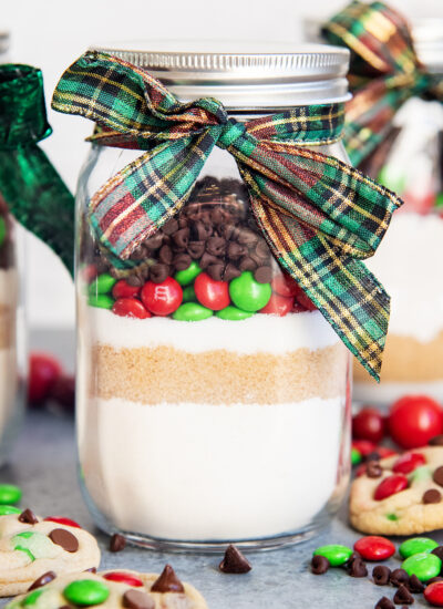 A jar of dry cookie mix, with layers of flour, brown sugar, sugar, m&ms, and chocolate chips.