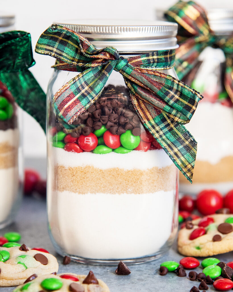 A jar of dry cookie mix, with layers of flour, brown sugar, sugar, m&ms, and chocolate chips.