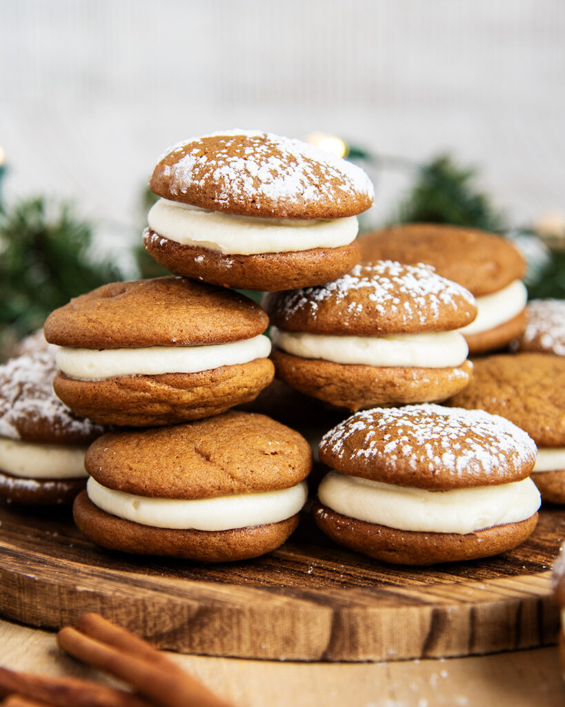 A pile of Gingerbread Whoopie pies on a wooden board.