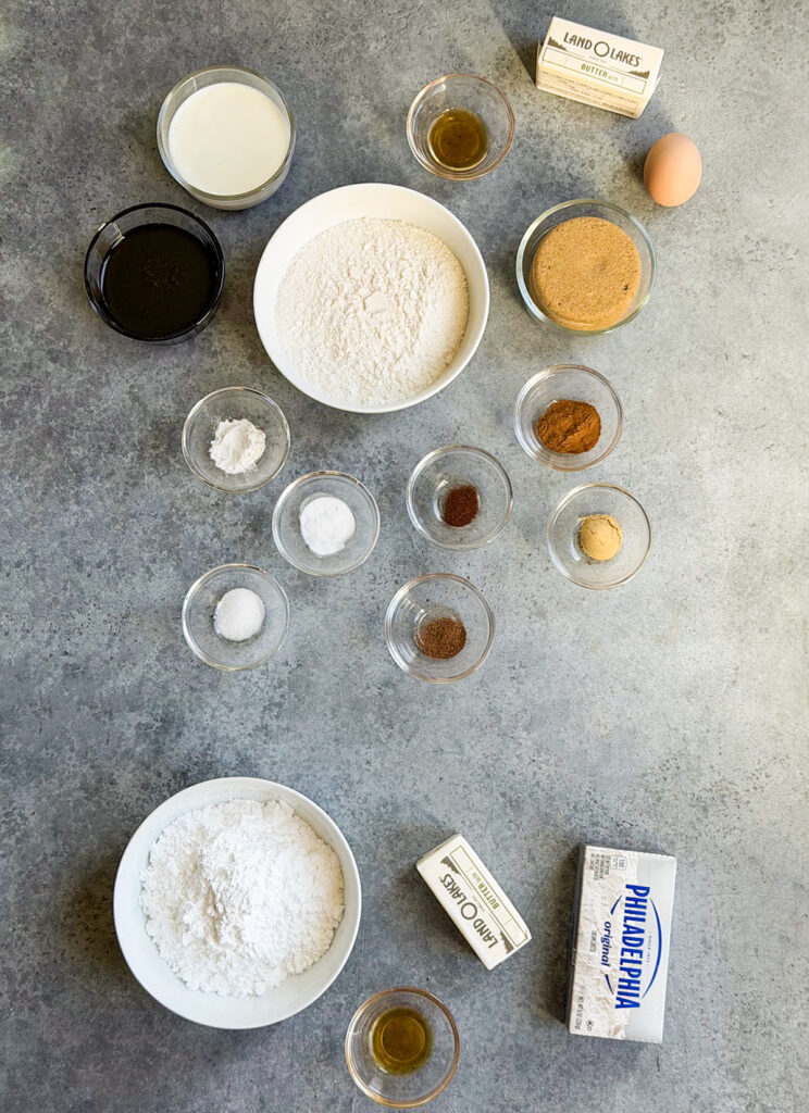 Small bowls of the ingredients needed to make gingerbread whoopie pies including flour, brown sugar, molasses, cream cheese, butter, an egg, and spices. 