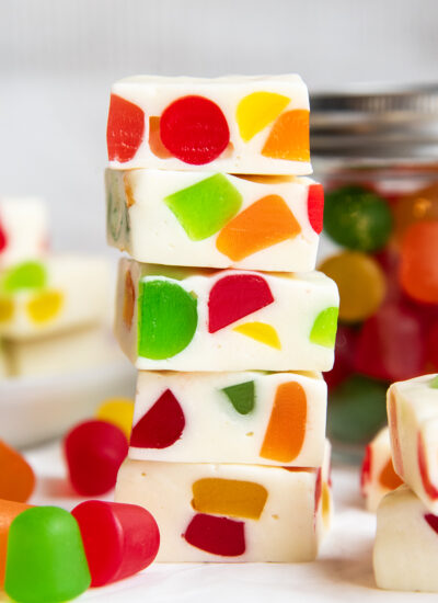 A stack of several pieces of homemade gumdrop nougat candy, filled with rainbow gumdrop candies.