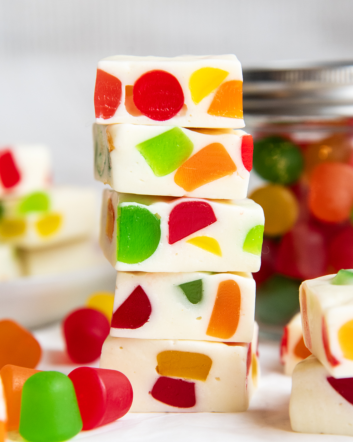 A stack of several pieces of homemade gumdrop nougat candy, filled with rainbow gumdrop candies.