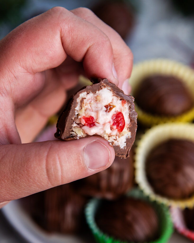 A child's hand holding half of a martha washington candy showing the inside of the candy.