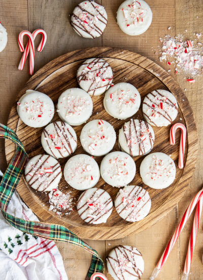 An above view of peppermint bark white chocolate Oreos on a wooden board.
