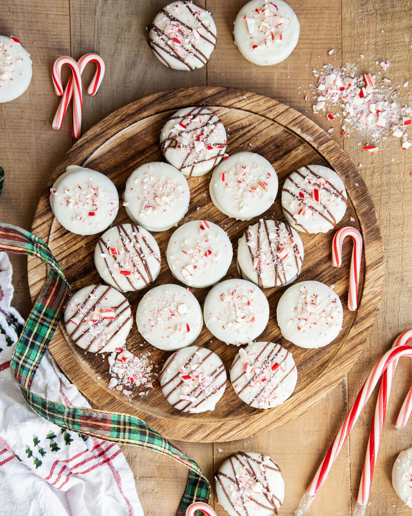 An above view of peppermint bark white chocolate Oreos on a wooden board.