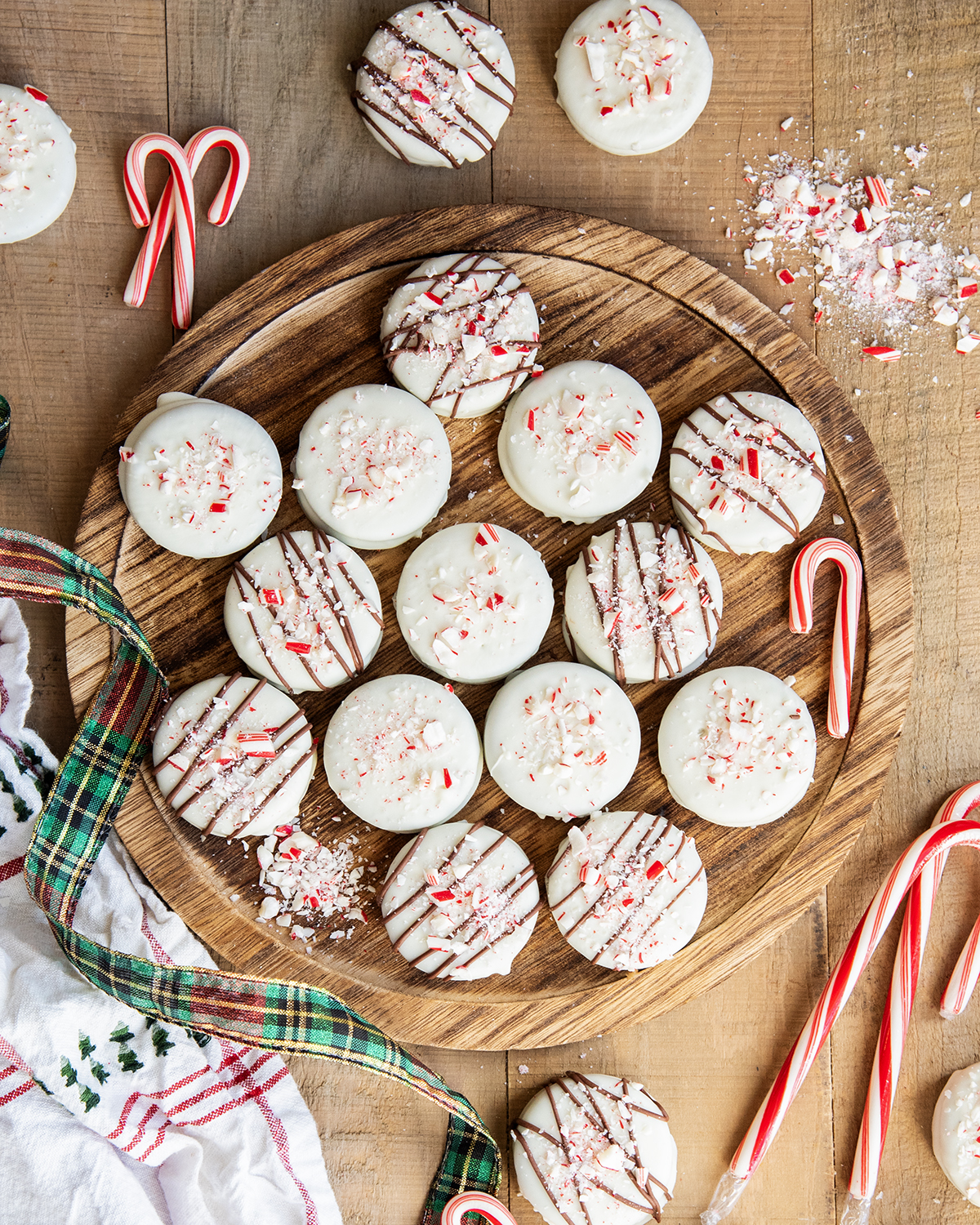 An above view of peppermint bark white chocolate Oreos on a wooden board.