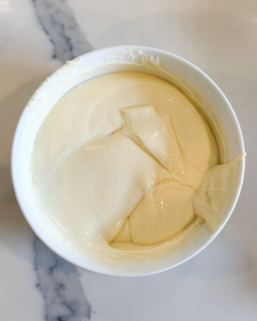Melted white chocolate in a white bowl.
