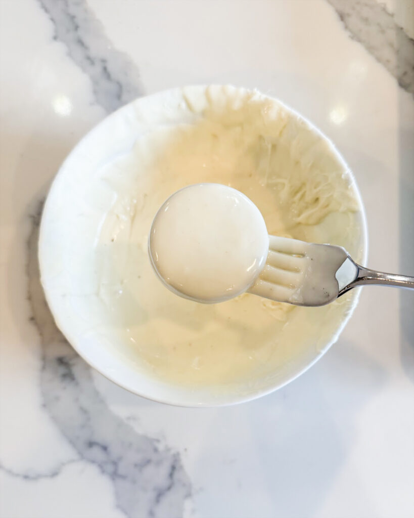 A white chocolate coated Oreo on a fork.