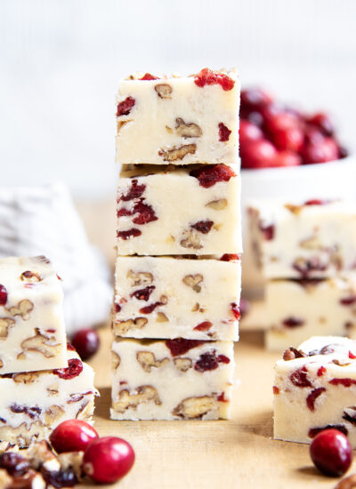 A tall stack of white chocolate fudge full of pieces of pecans and dried cranberries.