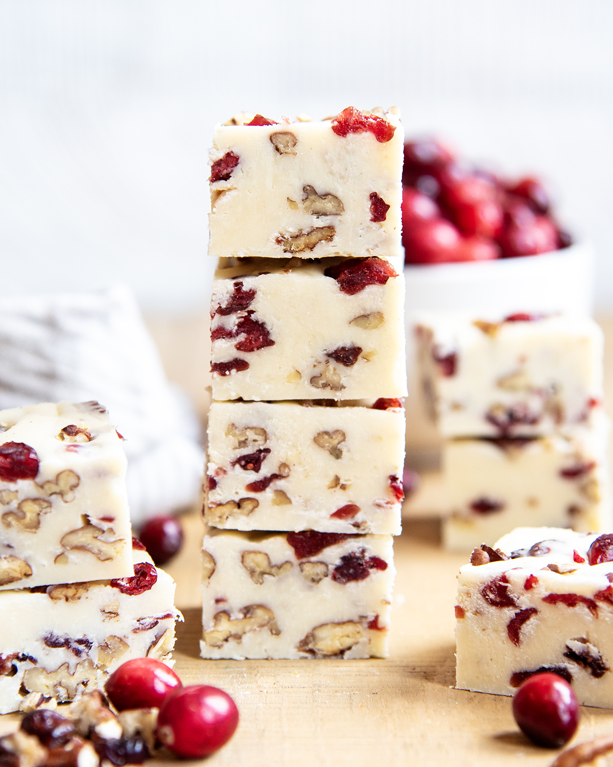 A tall stack of white chocolate fudge full of pieces of pecans and dried cranberries.