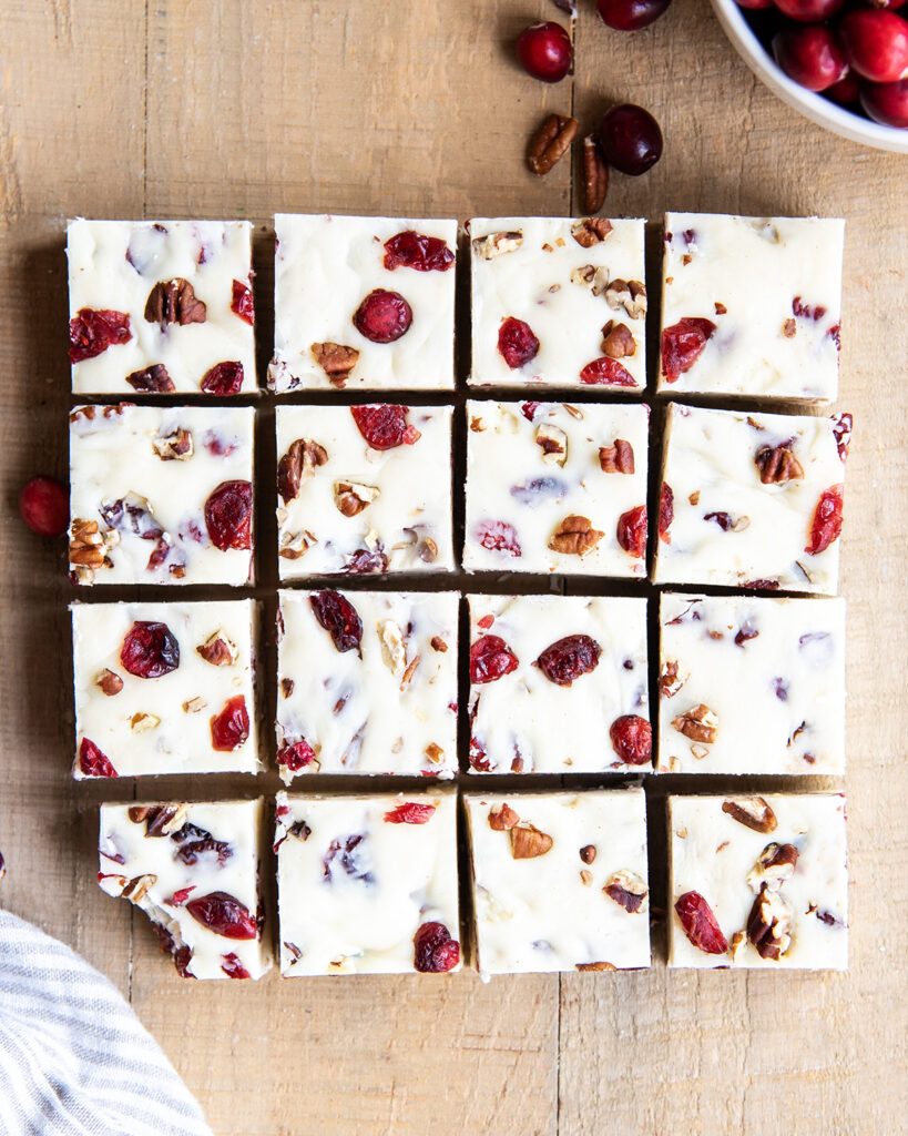 An above view of rows of white chocolate cranberry fudge with pecans.