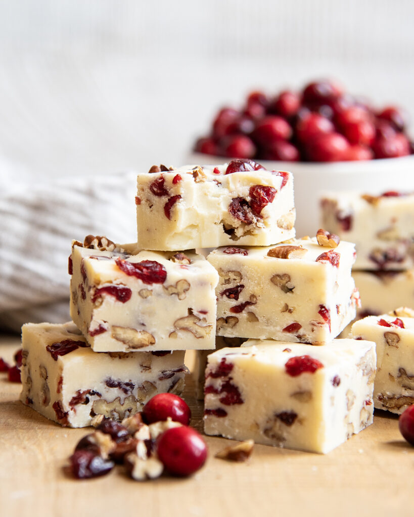 A pile of white chocolate cranberry and pecan fudge, and the top piece has a bite out of it.