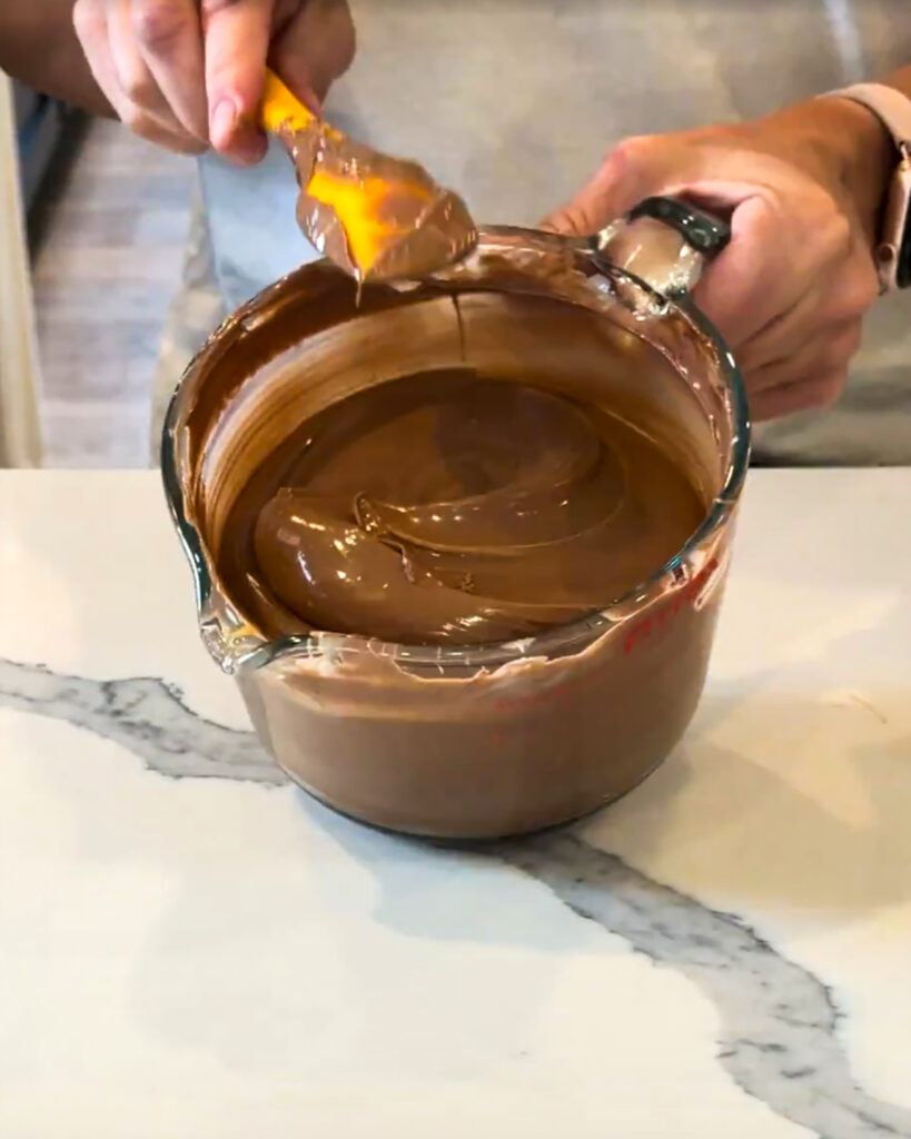 A glass bowl with melted chocolate in it.