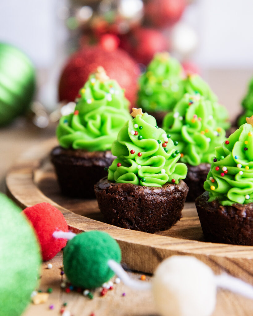 A side view of Christmas tree buttercreams piped on brownie bites.