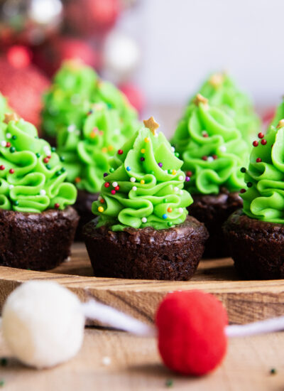 A side view of Christmas tree buttercreams piped on brownie bites.