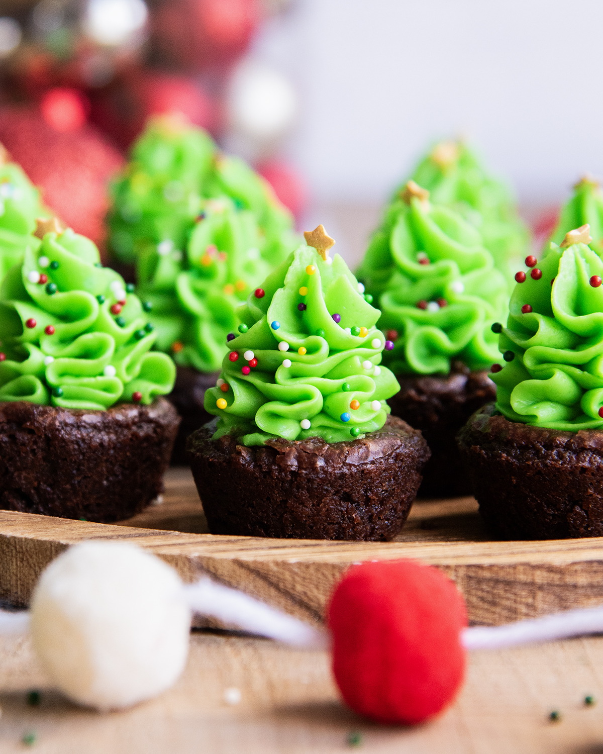 A side view of Christmas tree buttercreams piped on brownie bites.