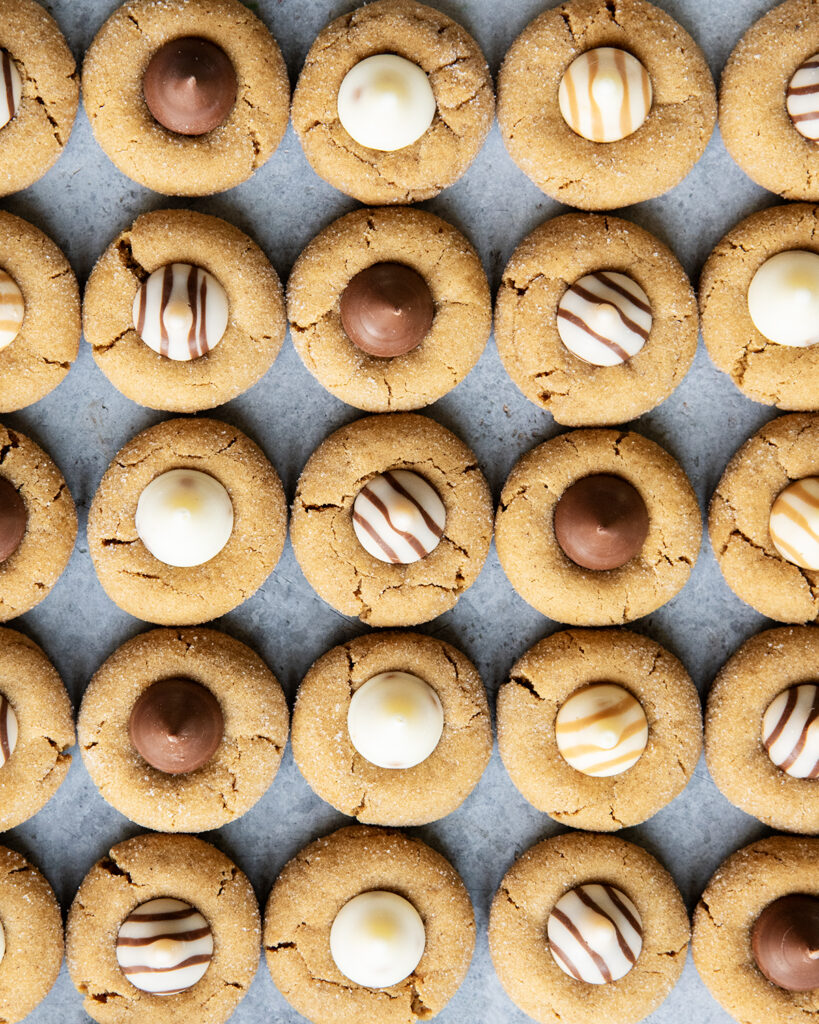 Rows of Ginger Blossom Cookies topped with hershey kisses and white chocolate hugs.