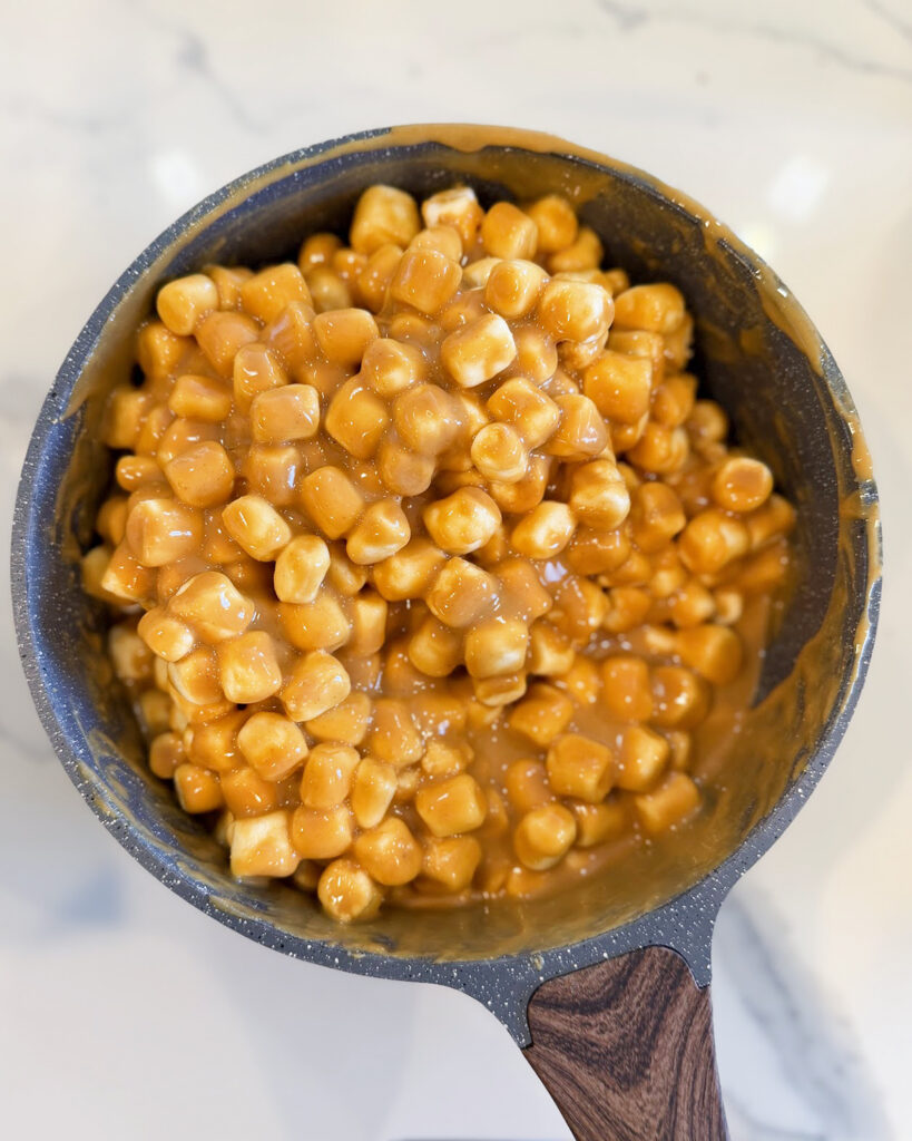 Peanut butter coating mini marshmallows in a pot.