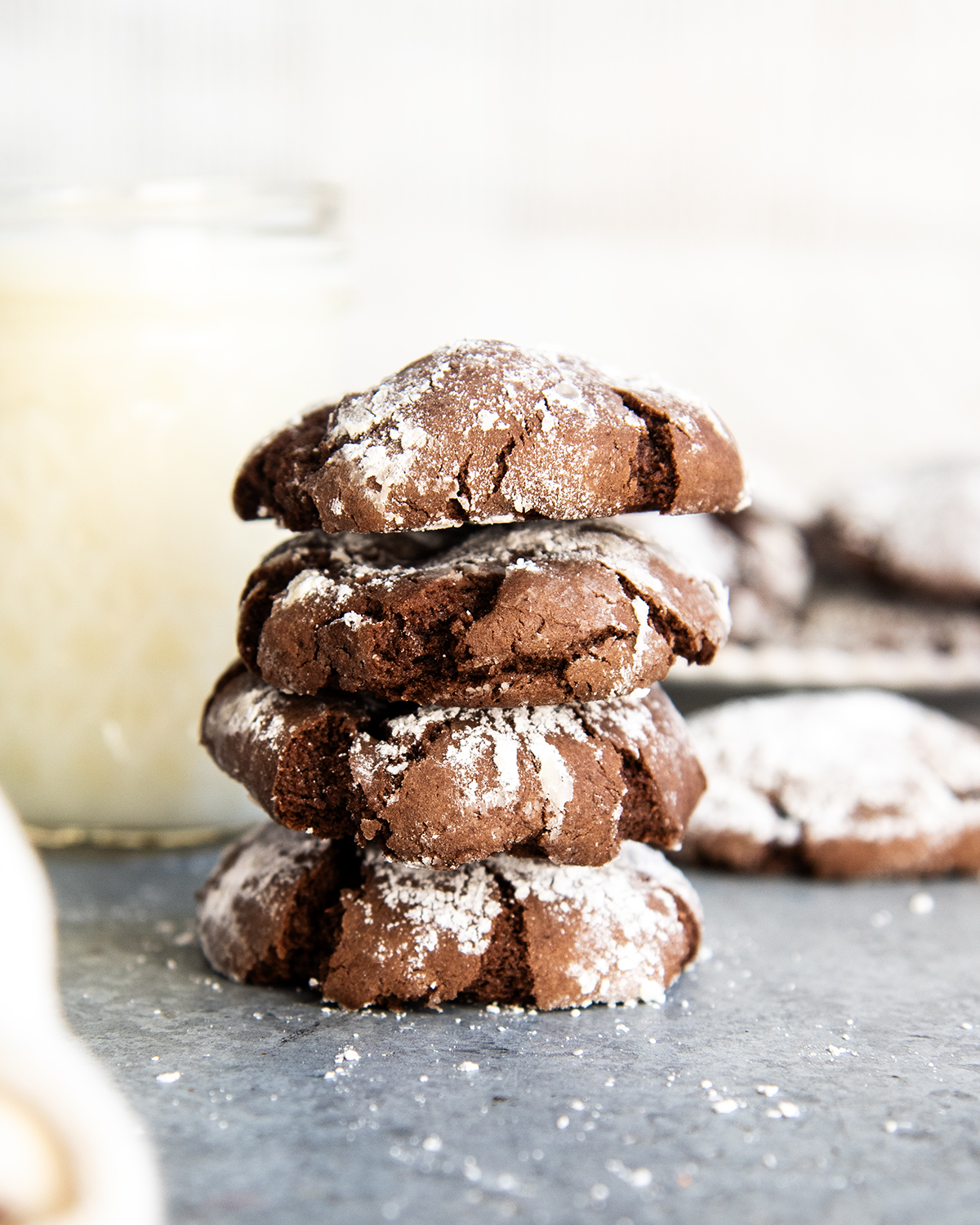 A stack of four chocolate cake mix crinkle cookies coated in powdered sugar.