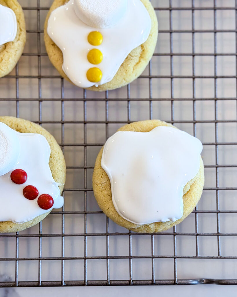 Cookies decorated with royal icing and mini m&ms to look like a puddle of melted snow. 