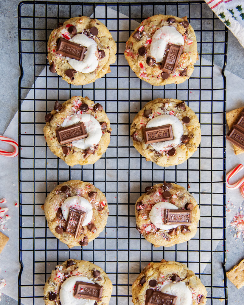 Rows of smores and peppermint chocolate chip cookies topped with half a marshmallow and hershey chocolate pieces.