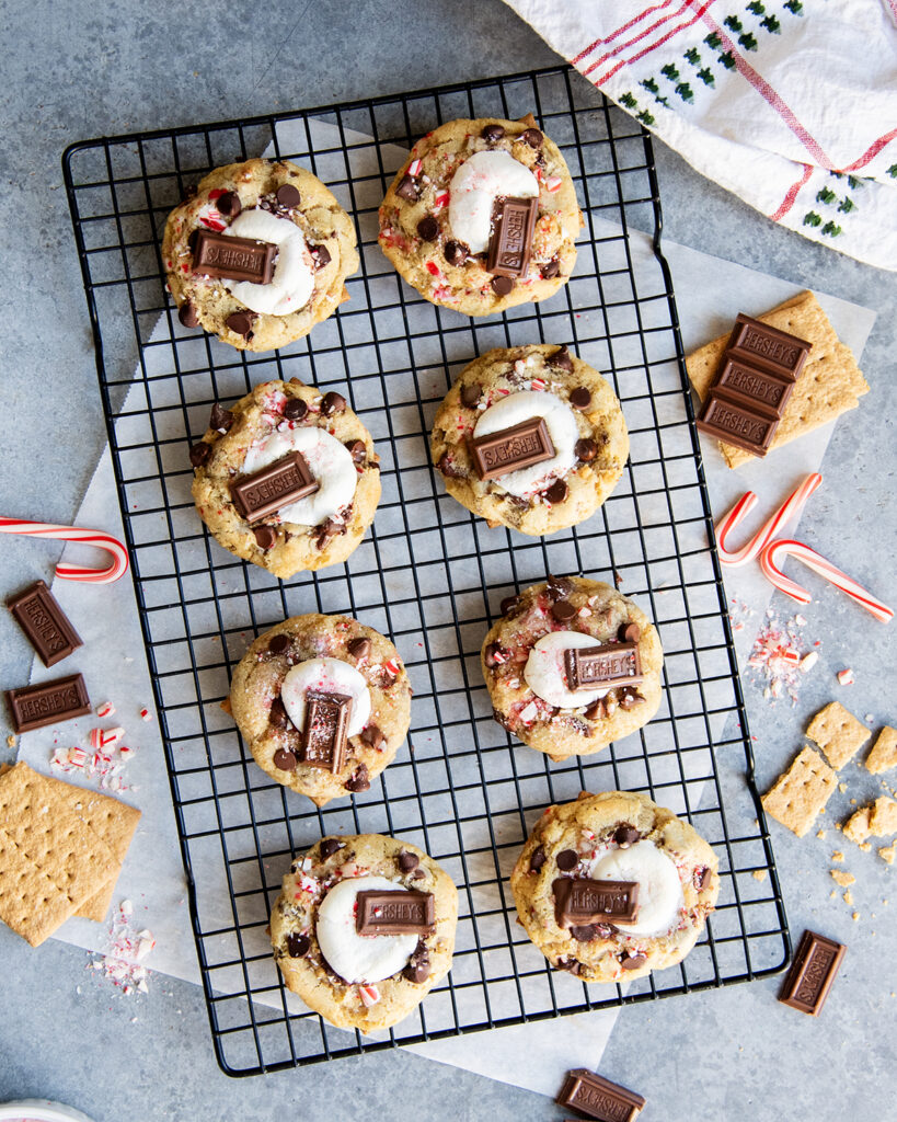 Rows of smores and peppermint chocolate chip cookies topped with half a marshmallow and hersheys chocolate pieces.