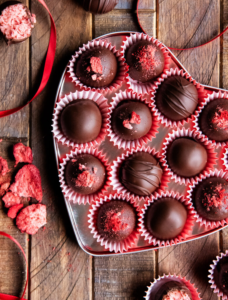 A heart shaped tin full of strawberry cream chocolates.