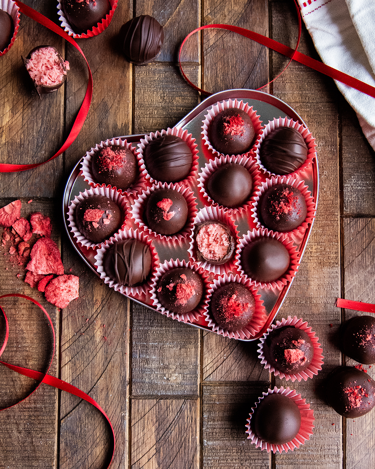 A heart shaped tin full of strawberry cream chocolates.