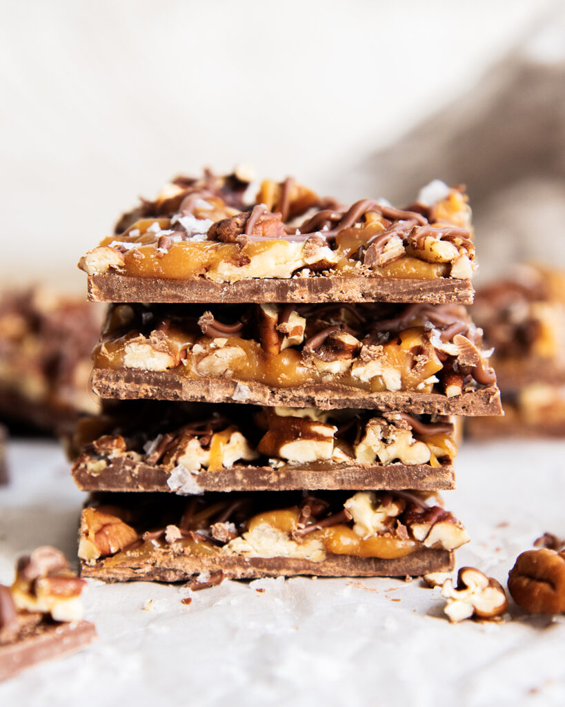 A stack of four pieces of chocolate caramel pecan bark.