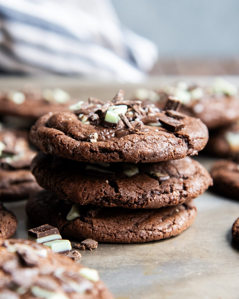A stack of three chocolate mint cookies stuffed with Andes Mint chocolates.