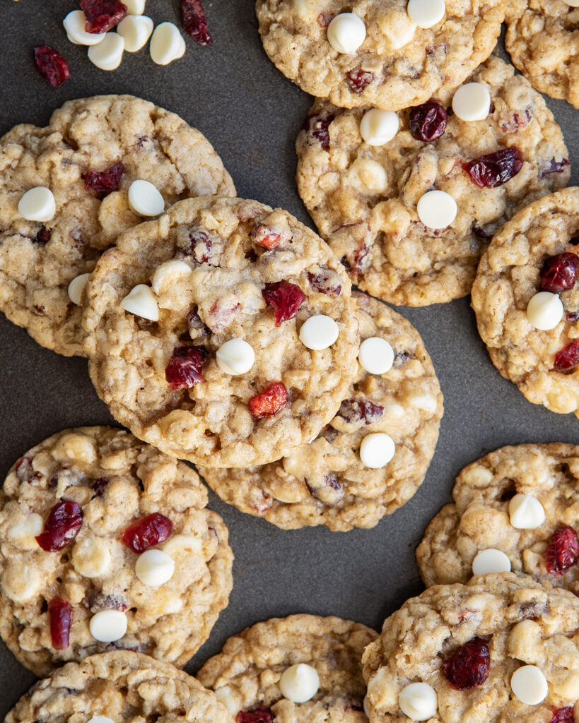 A cookie sheet with oatmeal cranberry white chocolate cookies on it.