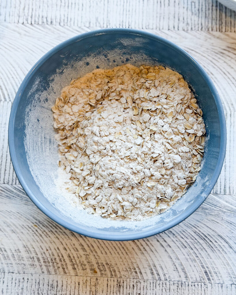 Oatmeal and flour mixed together in a blue mixing bowl.