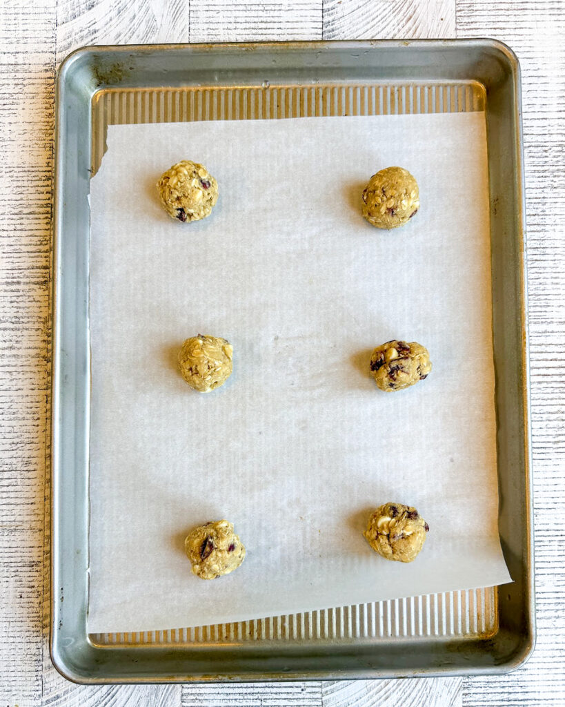 Oatmeal Cranberry White Chocolate Cookie Dough Balls on a parchment lined cookie sheet.