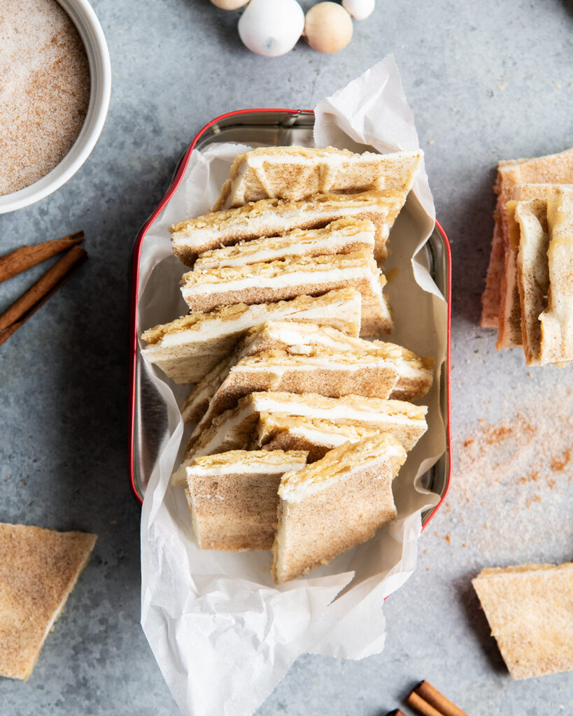 A stack of churro cracker toffee pieces in a metal tin.