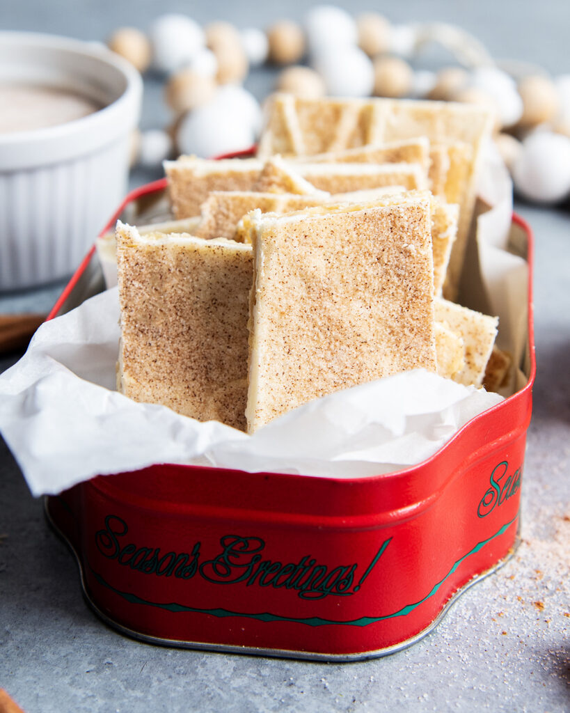 A row of churro cracker toffee pieces in a metal tin.
