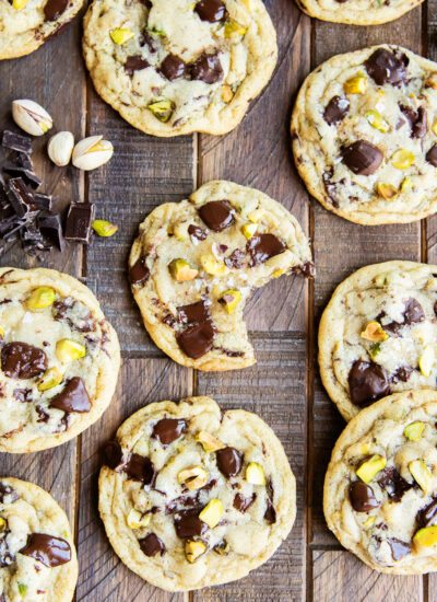 An above view of chocolate chip and pistachio cookies on a wooden table.