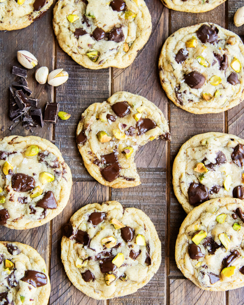 An above view of chocolate chip and pistachio cookies on a wooden table.