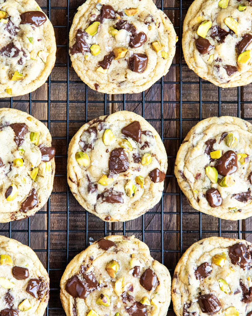 An above view of pistachio chocolate chip cookies on a black wire cooling rack.